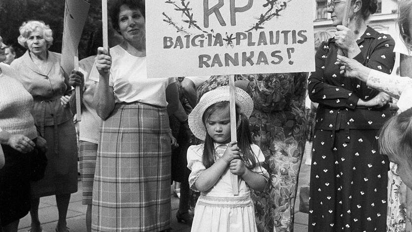 Situacija: pastebėjęs mergaitę balta suknele, prilaikančią ant žemės stovintį plakatą, fotografas paprašė mažylės jį iškelti. Skirmantė išpildė fotografo prašymą.