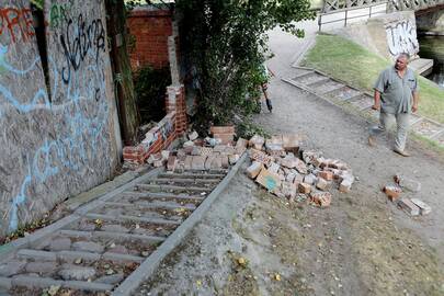 Pavojus: raudonų plytų tvoros dalis nugriuvo tiesiai ant tako.