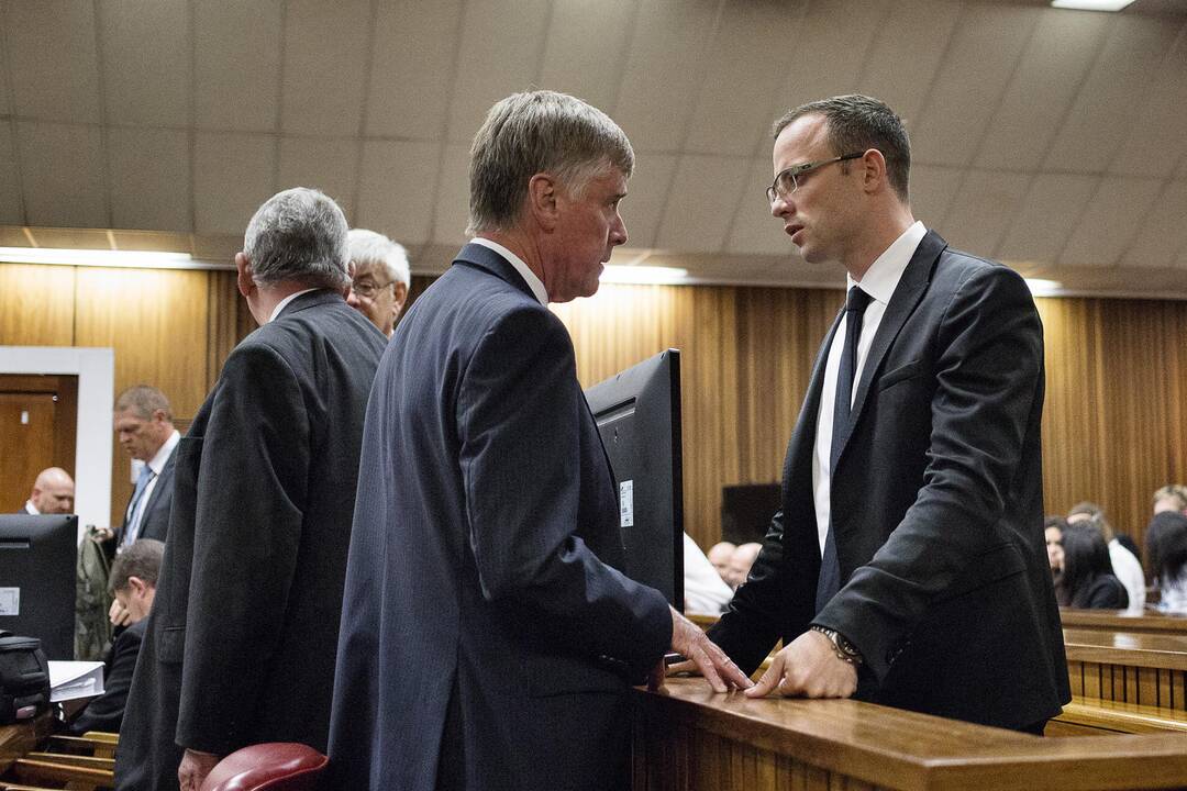 Oscaras Pistorius (dešinėje) teisme kalbasi su advokatais.
