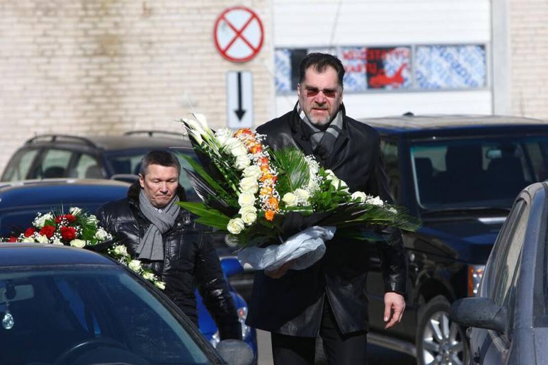Su I.Matijošaitiene atsisveikinantys žmonės neša baltas gėles 