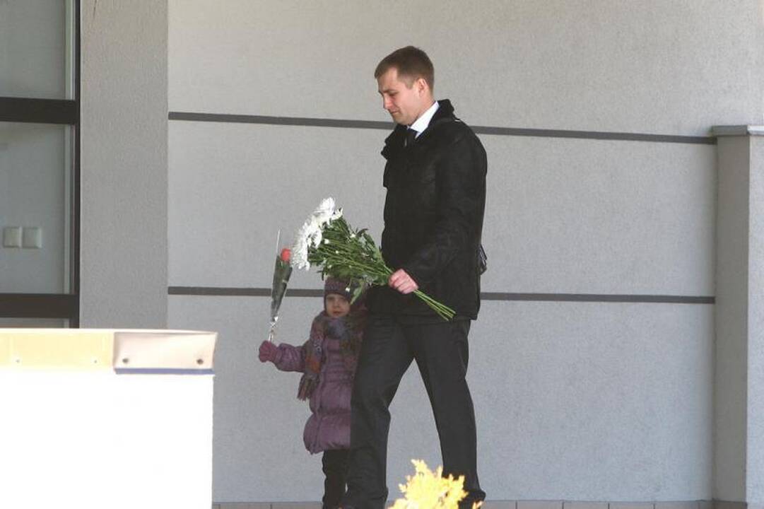 Su I.Matijošaitiene atsisveikinantys žmonės neša baltas gėles 