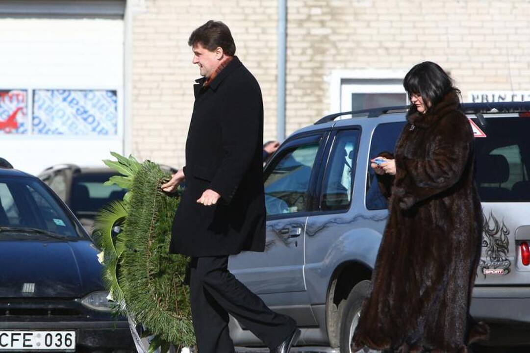 Su I.Matijošaitiene atsisveikinantys žmonės neša baltas gėles 