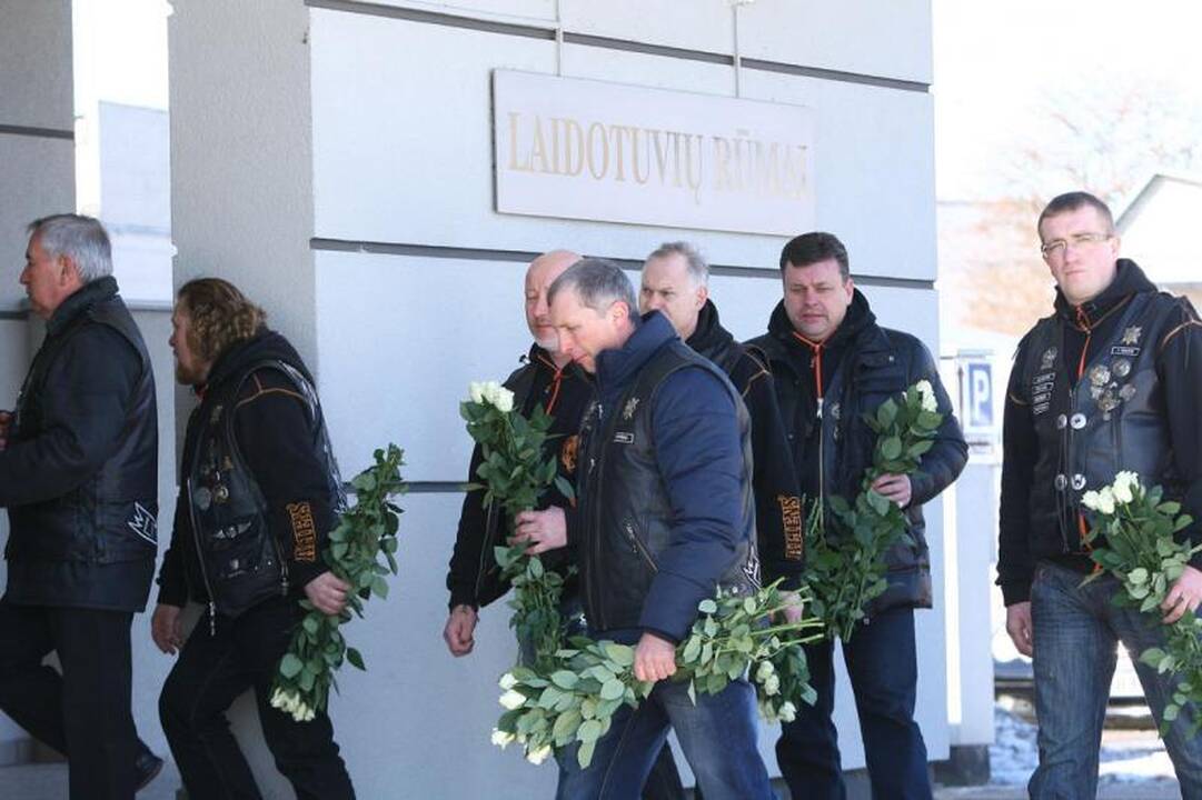 Su I.Matijošaitiene atsisveikinantys žmonės neša baltas gėles 