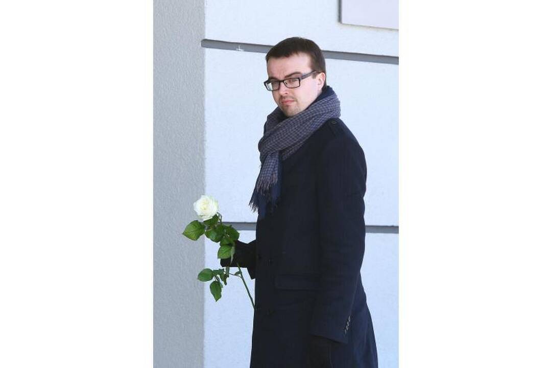 Su I.Matijošaitiene atsisveikinantys žmonės neša baltas gėles 