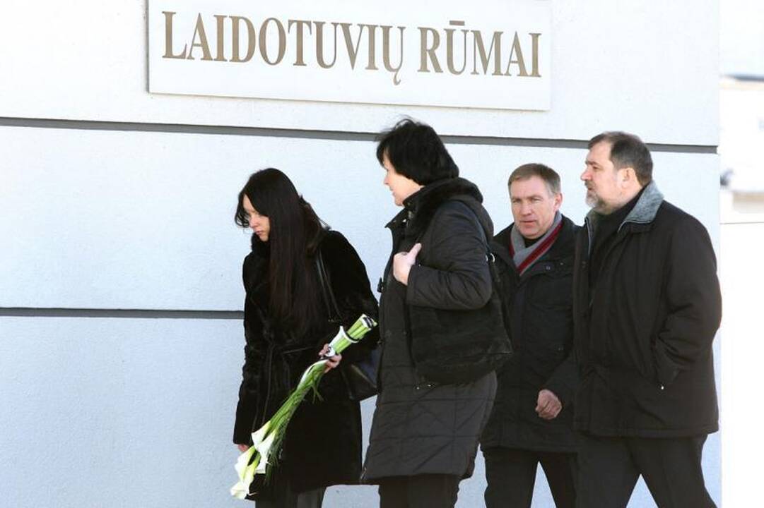 Su I.Matijošaitiene atsisveikinantys žmonės neša baltas gėles 