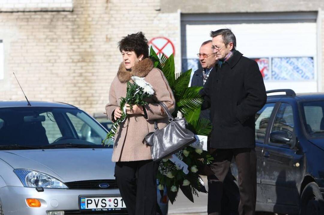 Su I.Matijošaitiene atsisveikinantys žmonės neša baltas gėles 