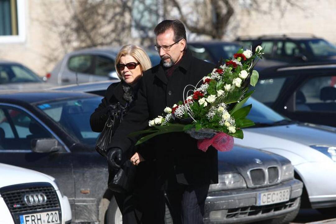 Su I.Matijošaitiene atsisveikinantys žmonės neša baltas gėles 