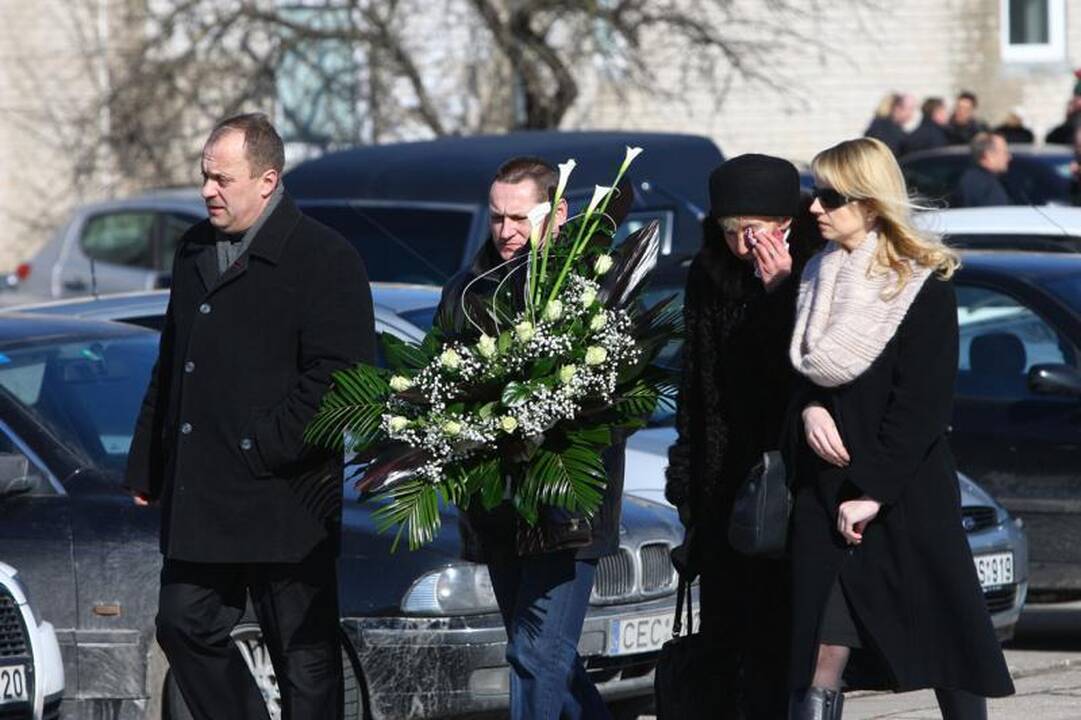 Su I.Matijošaitiene atsisveikinantys žmonės neša baltas gėles 