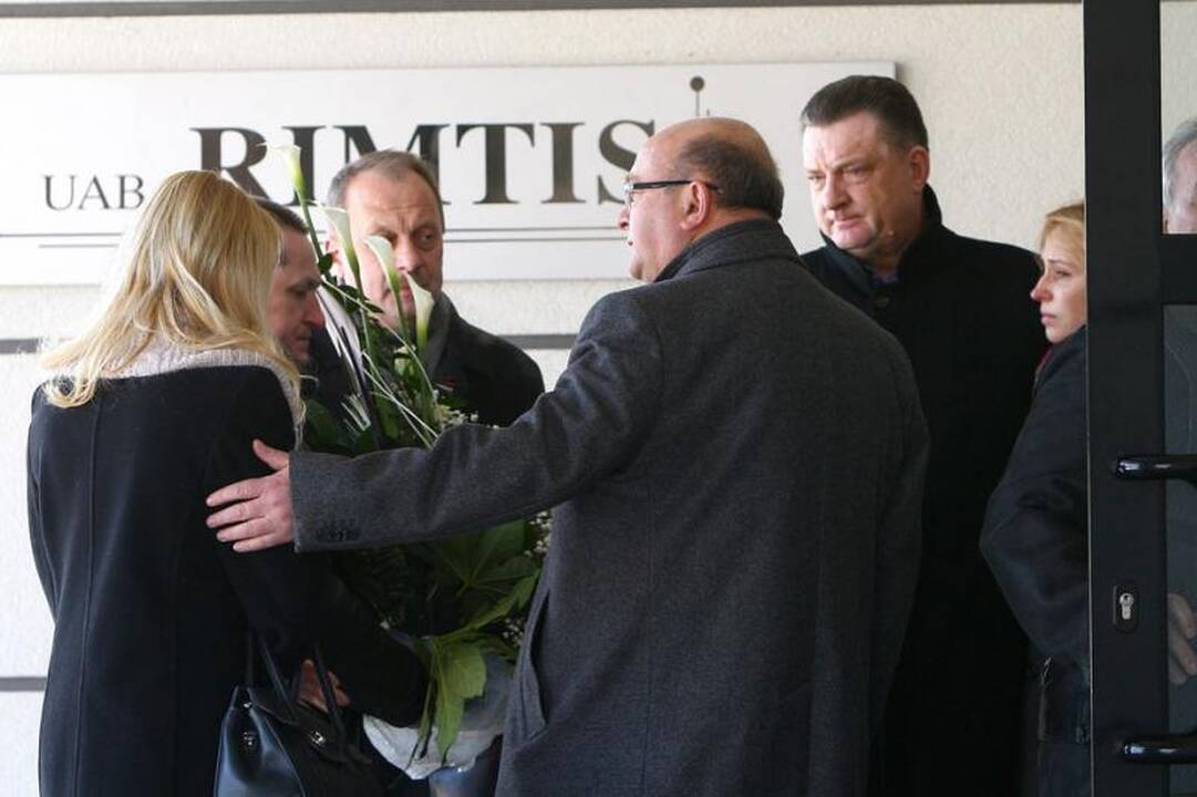 Su I.Matijošaitiene atsisveikinantys žmonės neša baltas gėles 