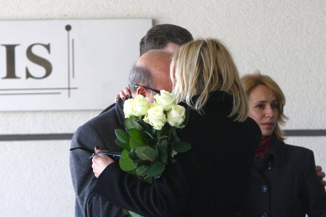 Su I.Matijošaitiene atsisveikinantys žmonės neša baltas gėles 