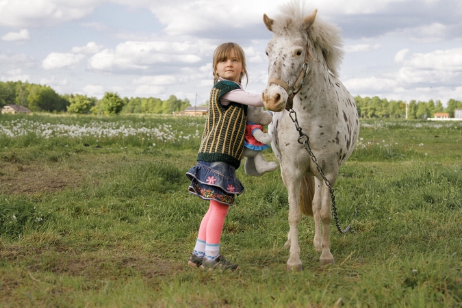 Mergaitė, jau trejų sėdėjusi balne