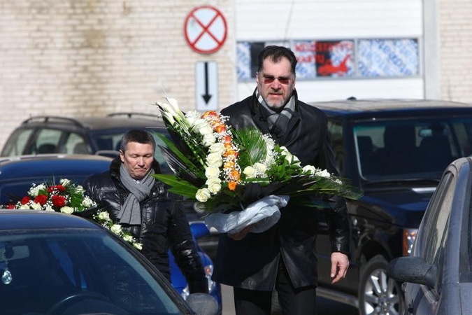 Su I.Matijošaitiene atsisveikinantys žmonės neša baltas gėles 